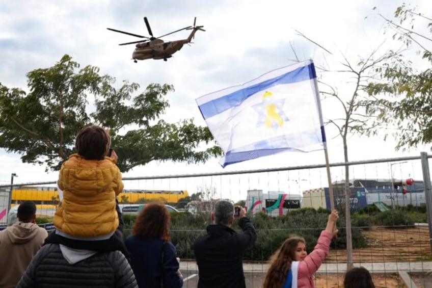 People wave an Israeli flag as they watch a military helicopter transporting a newly-relea