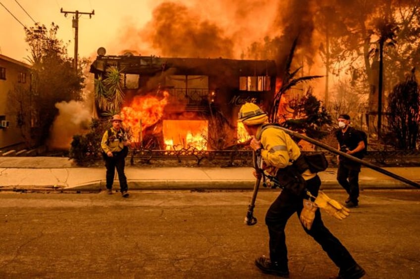 Firefighters work as an apartment building burns in the Altadena area of Los Angeles count