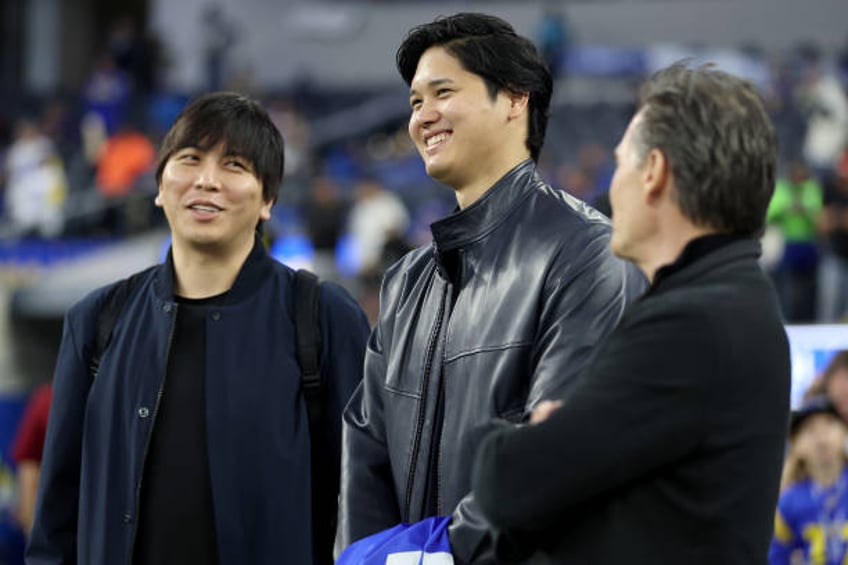 Shohei Ohtani of the Los Angeles Dodgers talks with his interpreter Ippei Mizuhara and agent Nez Balelo prior to the game between the New Orleans...