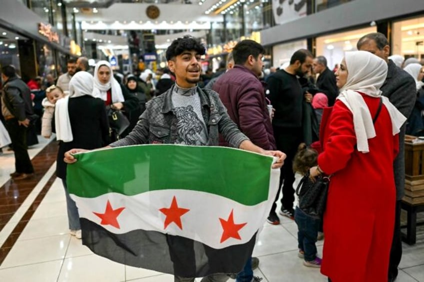 A young man holds a Syrian independence flag in a shopping mall near Sarmada, in the north