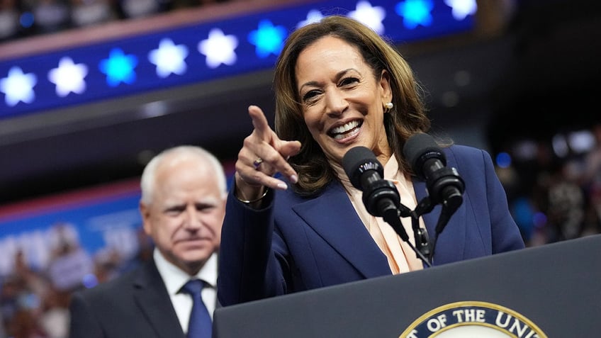 Kamala Harris pointing and laughing in closeup shot, Gov. Walz behind her