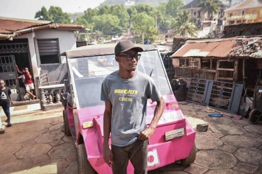 Self-taught innovator James Samba stands in front of an eco-friendly electric vehicle he m