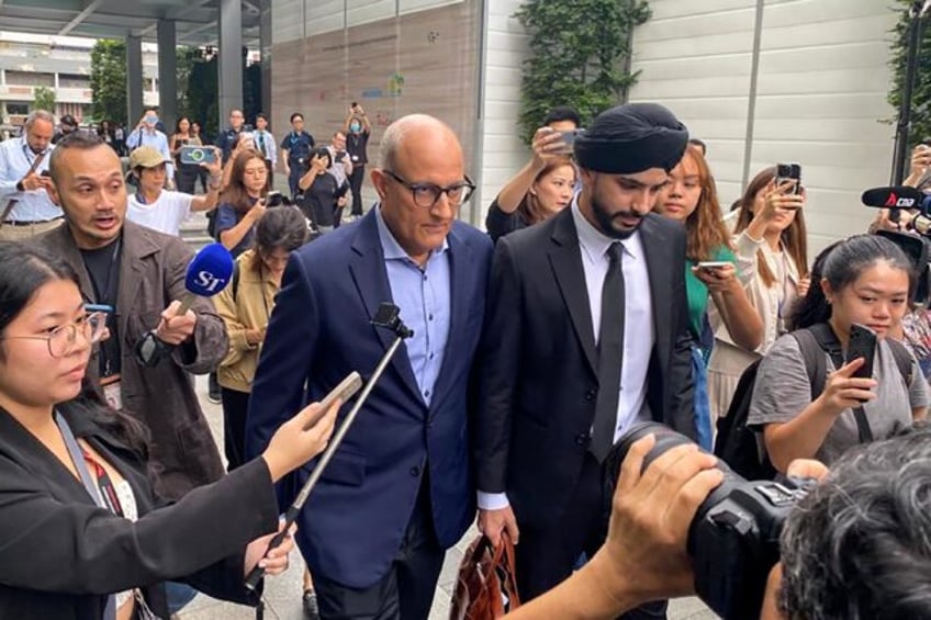 Singaporean transport minister S. Iswaran (centre L) leaves court after an appearance on T