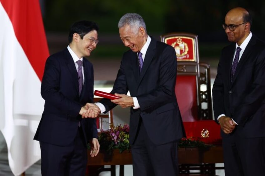 Lawrence Wong (L) is sworn in as Singapore's new prime minister and shakes hands with form