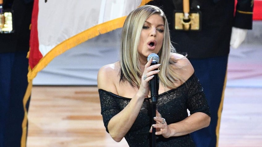 Fergie In a black off the shoulder dress sings animatedly into the microphone at the NBA All-Star Game