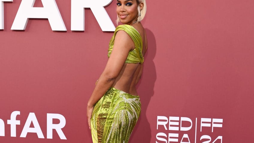 Kelly Rowland poses in a green dress at the amfAR gala