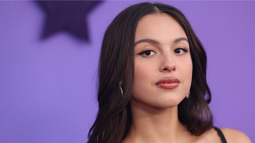 Olivia Rodrigo looks slightly to her right on the carpet, semi-mysteriously