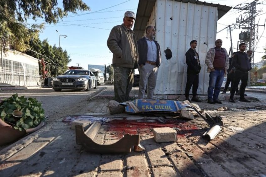 People look at a pool of blood where one six Palestinians was killed during an Israeli raid in Jenin, the occupied West Bank