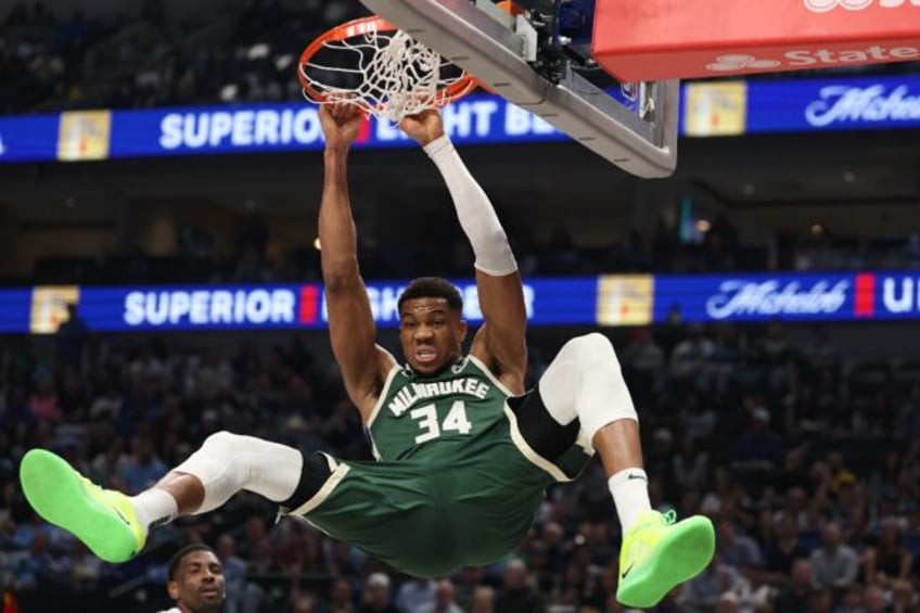 Milwaukee's Giannis Antetokounmpo hangs on the rim after a dunk in the Bucks' NBA victory