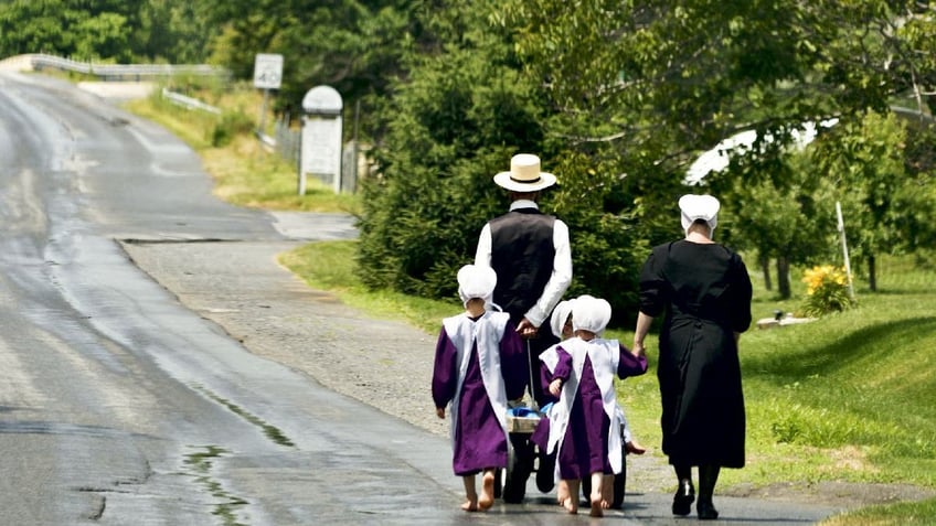 Amish family walks down road.