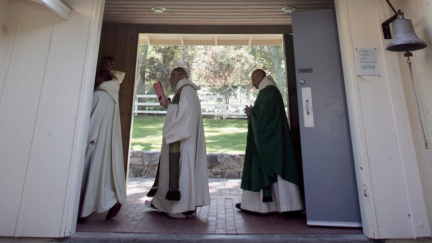 Monks head to noon Mass through a breezeway at St. Andrew's Abbey chapel in Valyermo.