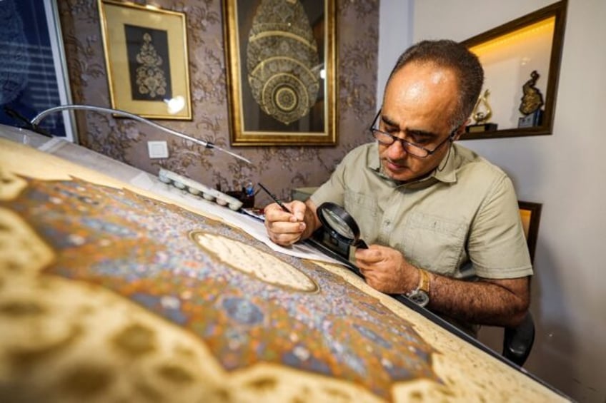 Mohammad Hossein Aghamiri, an artist who specialises in Persian miniatures, uses a magnify