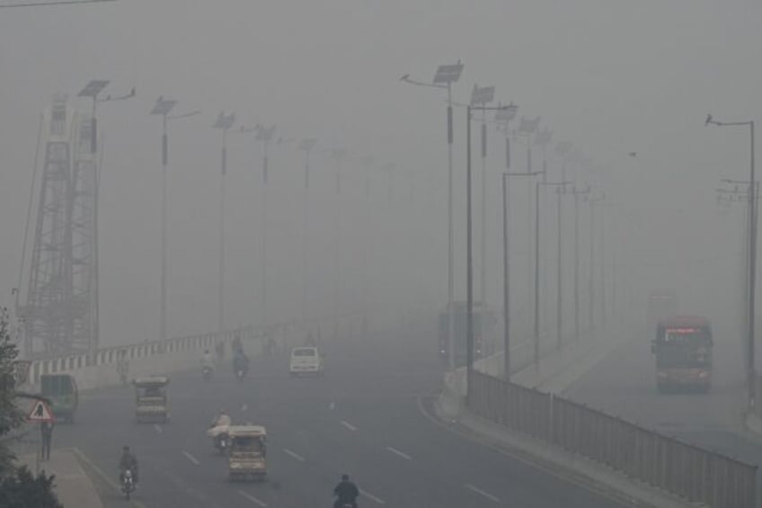 Commuters drive along a road amid heavy smog in Lahore