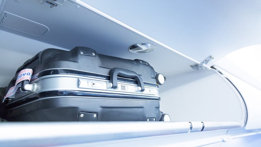 A flight passenger has sparked debate after spotting a suitcase hidden behind a cabin curtain on a flight — rather than being properly stored in an overhead bin.