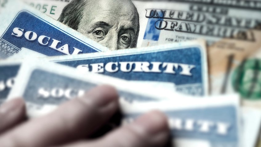 Several Social Security cards are pictured on a $100 bill.