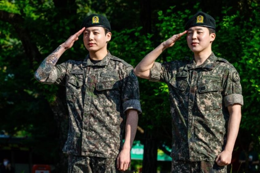 BTS members Jungkook (L) and Jimin (R) salute after their release from South Korean mandat