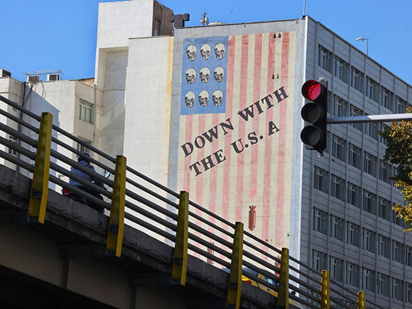 A man rides his motorbike over a bridge in Tehran facing the landmark anti-US mural painte