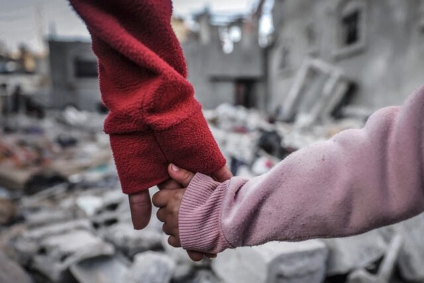 People hold hands as they inspect buildings hit during Israel's bombardment in Rafah in the southern Gaza Strip on December 29, 2023