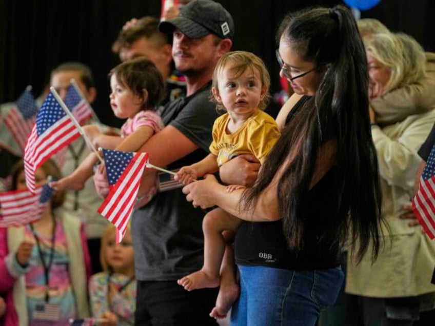 Afrikaner refugees from South Africa holding American flags arrive, Monday, May 12, 2025,