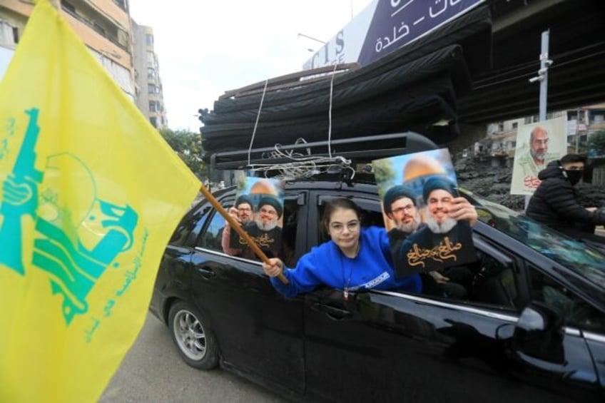 A Lebanese woman holds up portraits of Hezbollah's slain leaders Hassan Nasrallah and Hash