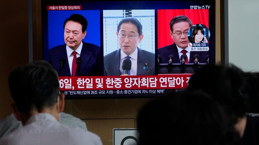 A TV screen shows file images of South Korean President Yoon Suk Yeol, left, Japanese Prime Minister Fumio Kishida and Chinese Premier Li Qiang, right, during a news program at the Seoul Railway Station in Seoul, South Korea.