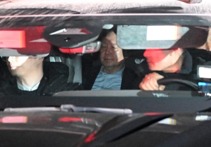 Impeached South Korean President Yoon Suk Yeol (C) is seen inside a vehicle as he leaves t