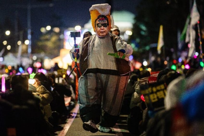 A demonstrator wearing a costume depicting South Korea President Yoon Suk Yeol walks among