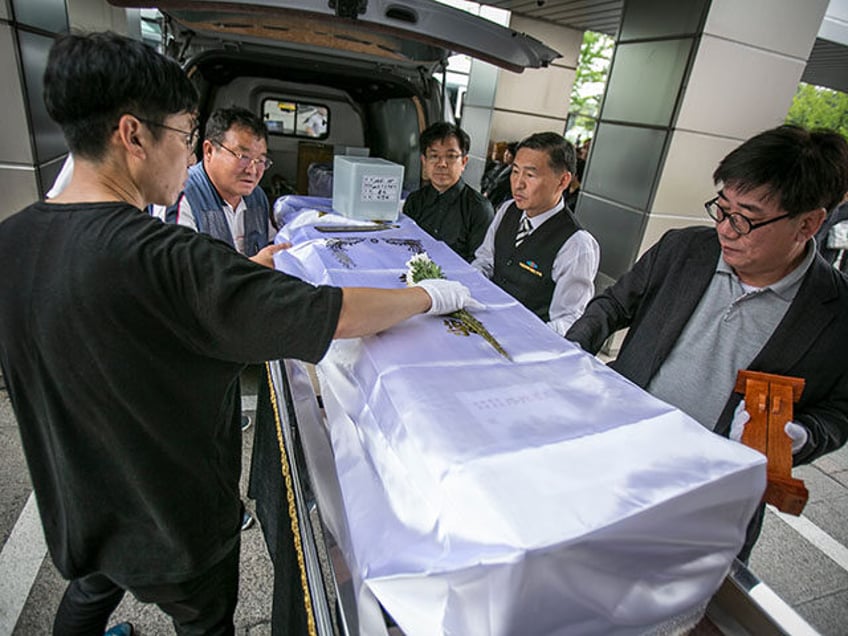 A volunteer Christian pastor (R), staff for Eunpyeong village funeral service, and staff for Good Nanum, place a coffin of a man, who died lonely at home and hospitals, on a platform at a crematoriumon July 4, 2016 in Goyang, South Korea. Good Nanum holds funerals for people whose remains …