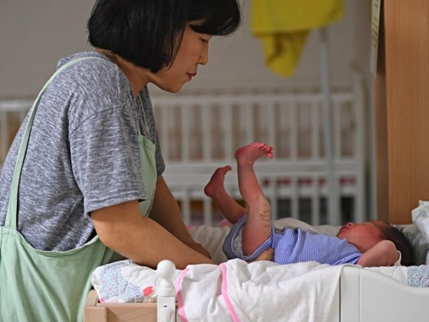 This photo taken on May 24, 2017 shows a social worker caring for a baby at the Jusarang C