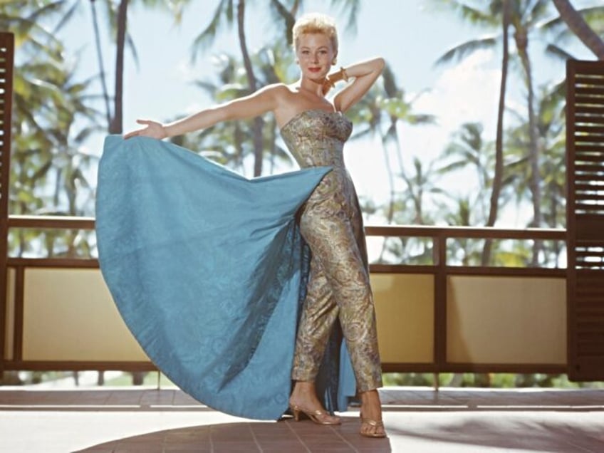 Mitzi Gaynor poses in glamorous gown by palm tress for the 1958 film version of 'South Pac