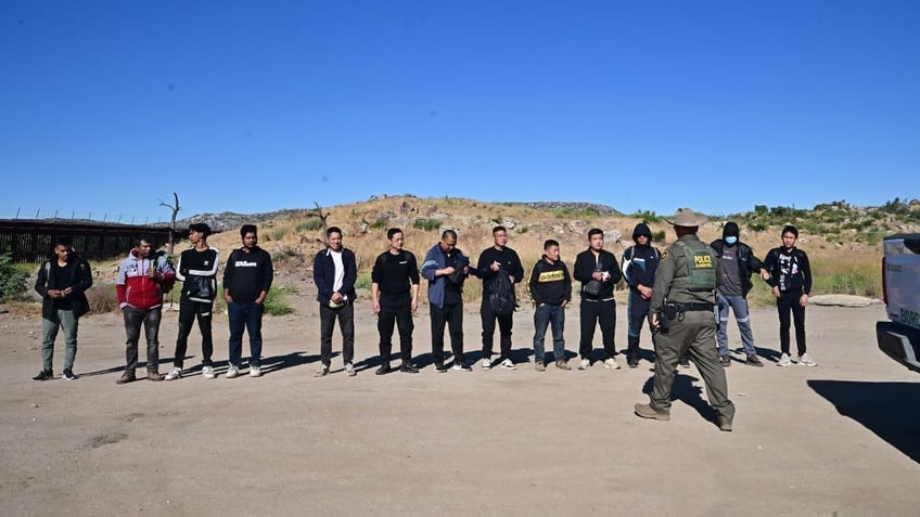 border officer with line of Chinese migrants on road 