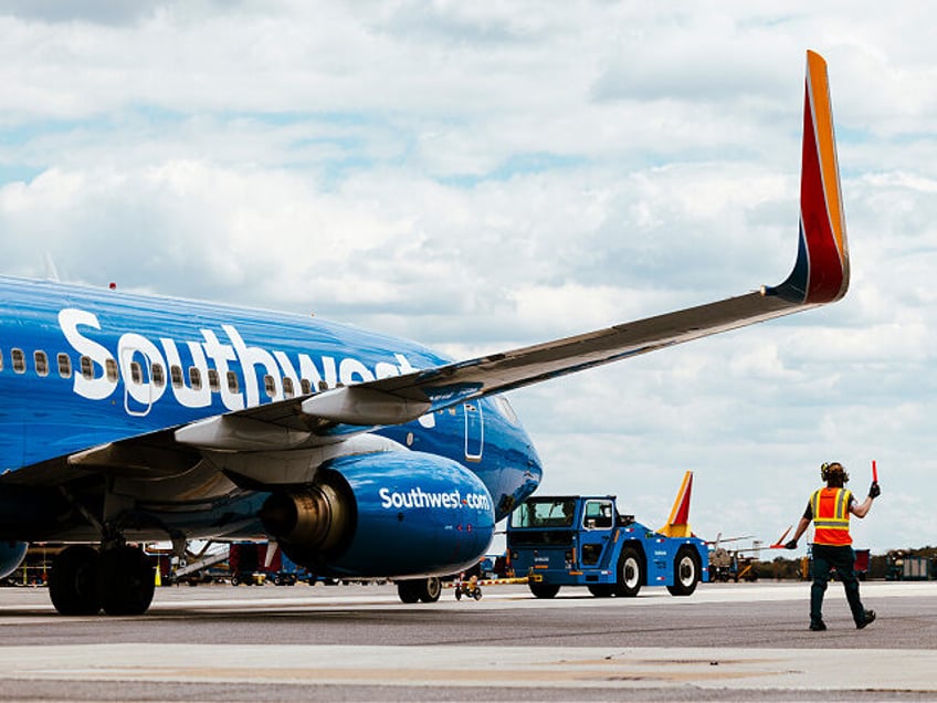 A ramp agents walks under the wing of a Southwest Airlines Boeing 737-700 airplane as it i