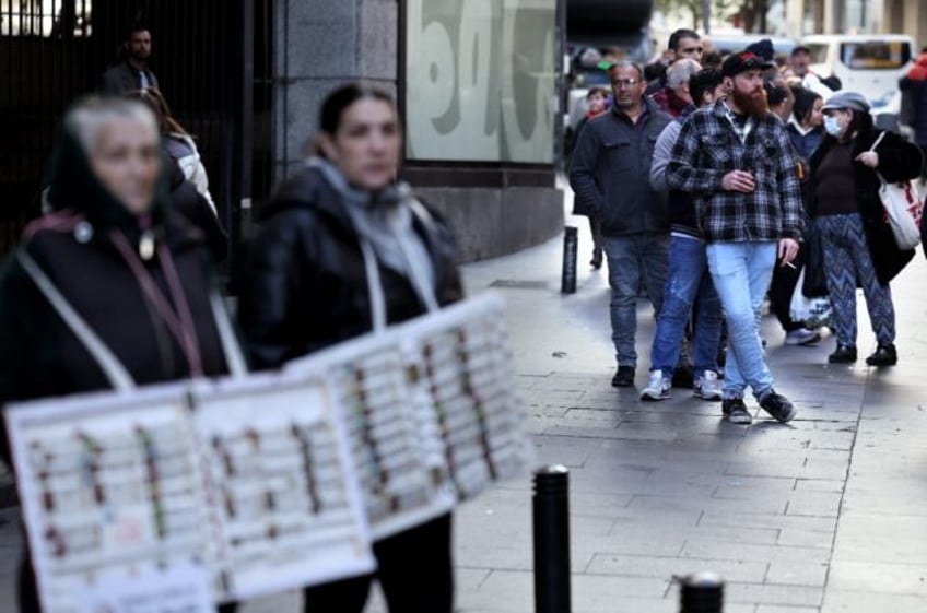 Spanish citizens and tourists spend hours in a queue to buy a ticket in Spain's popular Christmas lottery "El Gordo" (the Fat One)