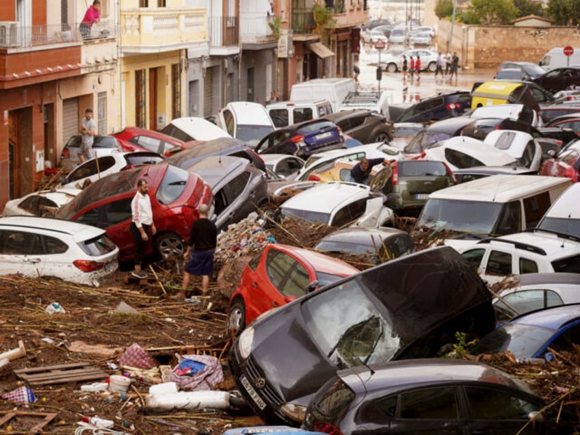 Residents look at cars piled up after being swept away by floods in Valencia, Spain, Wedne