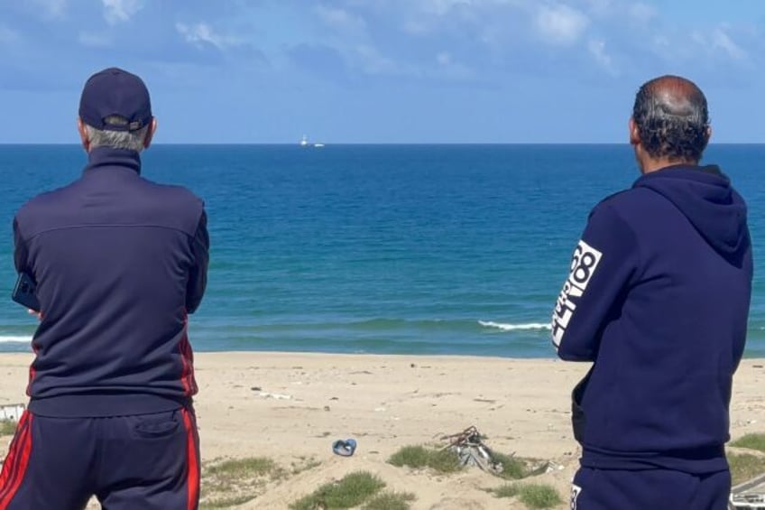 Palestinian men watch the Open Arms charity vessel bringing the first shipment of food aid