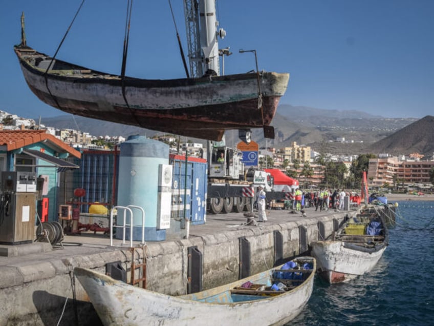 A crane hoists a boat, used by migrants, out of the water at Los Cristianos port as 41 mig