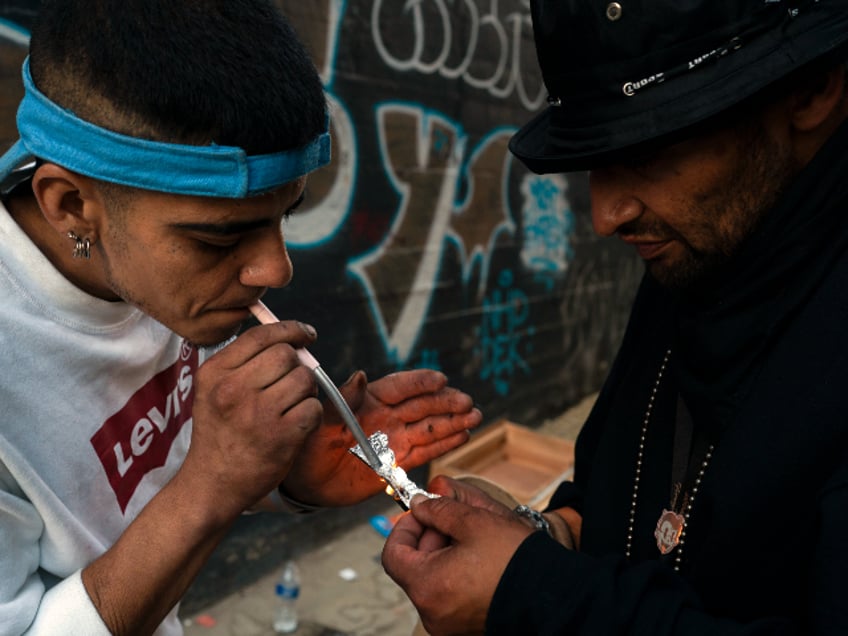 Two homeless addicts share a small piece of fentanyl in an alley in Los Angeles, Thursday, Aug. 18, 2022. Use of fentanyl, a powerful synthetic opioid that is cheap to produce and is often sold as is or laced in other drugs, has exploded. Two-thirds of the 107,000 overdose deaths in 2021 were attributed to synthetic opioids like fentanyl, the U.S. Centers for Disease Control and Prevention says. (AP Photo/Jae C. Hong)