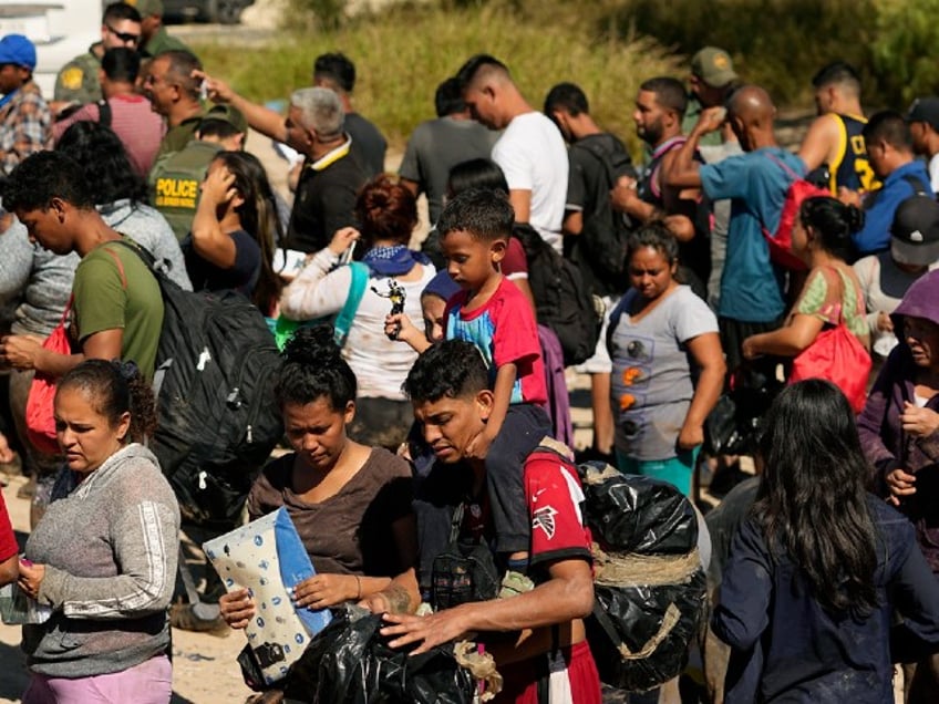 Migrants wait to be processed by the U.S. Customs and Border Patrol after they crossed the Rio Grande and entered the U.S. from Mexico, Thursday, Oct. 19, 2023, in Eagle Pass, Texas. Starting in March, Texas will give police even broader power to arrest migrants while also allowing local judges to order them out of the U.S. under a new law signed by Republican Gov. Greg Abbott. (AP Photo/Eric Gay)