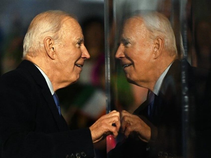 US President Joe Biden peers around a protective bullet=proof screen during a celebration