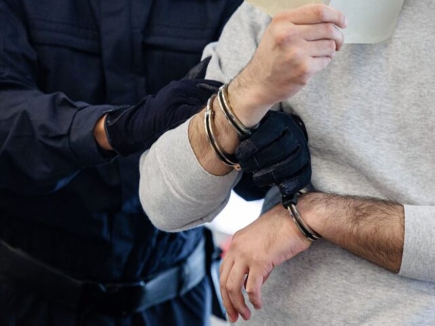 Defendant Abdul Majed R (R) is led in handcuffs into the courtroom of the Higher Regional