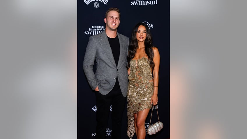 Christen Harper in a gold sparkling dress next to Jared Goff in a grey blazer and black shirt