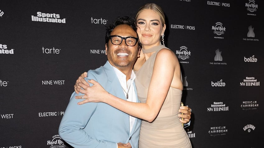 Kate Upton in a beige dress hugging Yu Tsai in a power blue suit.