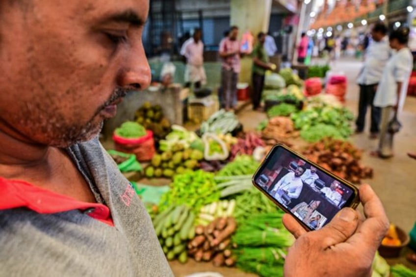 A man watches a live broadcast of Sri Lanka's President Anura Kumara Dissanayake presentin