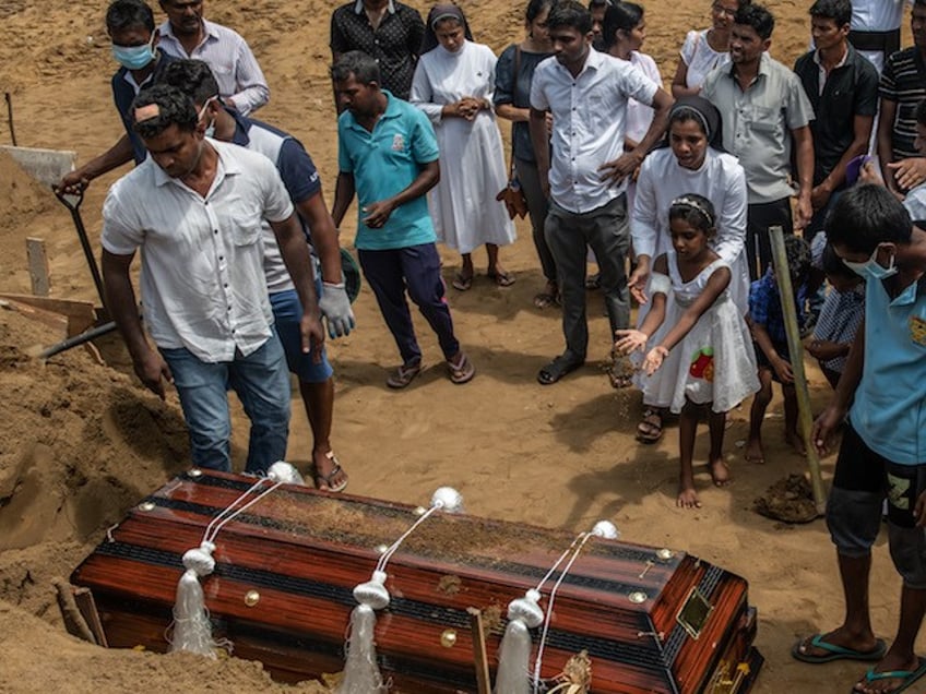 NEGOMBO, SRI LANKA - APRIL 24: A little girl throws earth on a coffin during the funeral of a person killed in the Easter Sunday attack on St Sebastian's Church, on April 24, 2019 in Negombo, Sri Lanka. At least 321 people were killed and 500 people injured after coordinated attacks on churches and hotels on Easter Sunday in and around Colombo as well as at Batticaloa in Sri Lanka. According to reports, the Islamic State group have claimed responsibility on Tuesday for the attacks while investigations show the attacks were carried out in retaliation for the Christchurch mosque shootings last month. Police have detained 40 suspects so far in connection with the suicide bombs while the government blame the attacks on local Islamist group National Thowheed Jamath (NTJ). (Photo by Carl Court/Getty Images)