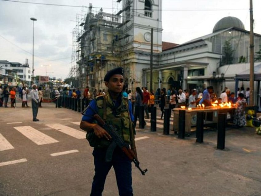 A Sri Lankan Navy personnel stands guard as Catholic devotees pray at St Anthony's church after it was partially opened for the first time since the Easter Sunday attacks in Colombo on May 7, 2019. - Sri Lanka's St Anthony's church partially opened for worship on May 7 even as security forces were rebuilding a shrine inside following the Easter suicide bombing. St Anthony's was among the three churches attacked by jihadi suicide bombers in coordinated attacks that also targeted three luxury hotels in Colombo on April 21. A total of 257 people were killed and nearly 500 wounded. At least 44 foreigners were among the dead. Nearly 50 of the victims were young children. (Photo by ISHARA S. KODIKARA / AFP) (Photo credit should read ISHARA S. KODIKARA/AFP/Getty Images)