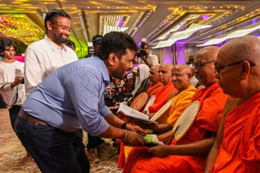 Sri Lanka's presidential hopeful Anura Kumara Dissanayaka, pictured distributing copies of