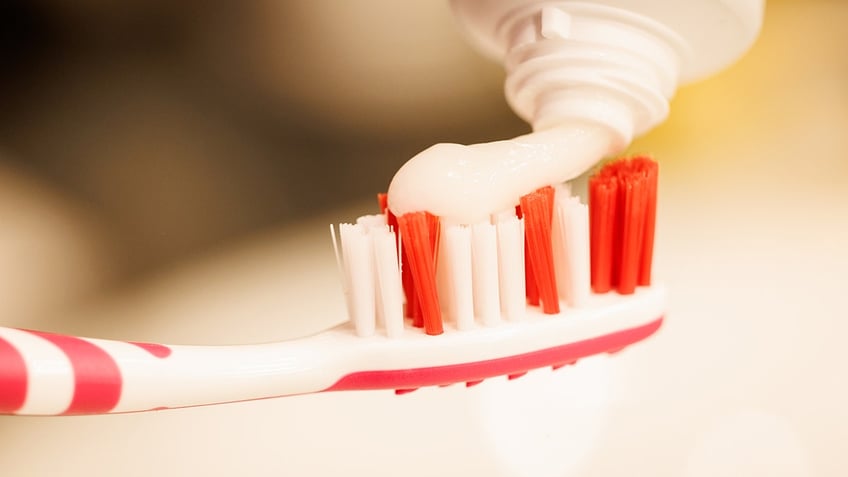 Toothpaste is placed atop a toothbrush