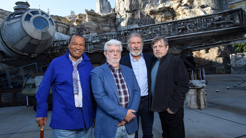 Billy Dee Williams posing alongside a group of men from Star Wars outside and smiling