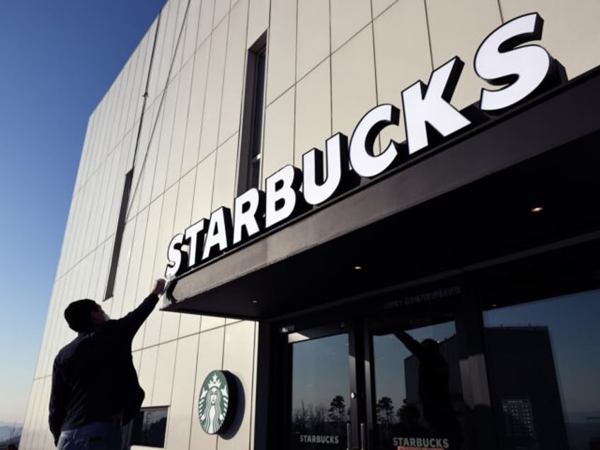 An employee wipes a sign at a Starbucks Coffee Korea Co. store, which has views of North K