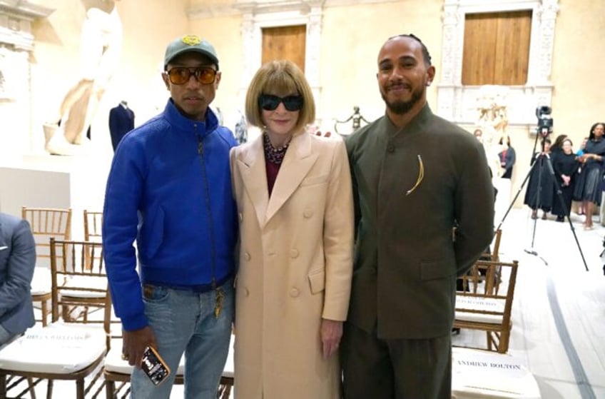 Pharrell Williams (L) and Lewis Hamilton (R), posing with Vogue editor Anna Wintour, are t